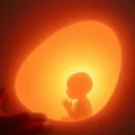 Um bebê no ventre materno, iluminado por uma luz divina, simbolizando o conhecimento de Deus.