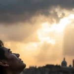 Pessoa refletindo sob um céu dramático, simbolizando a transformação.