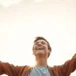 Pessoa feliz com braços abertos, simbolizando vida cristã além da religião.