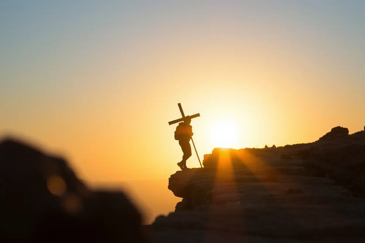 Homem carregando uma cruz em um caminho de subida