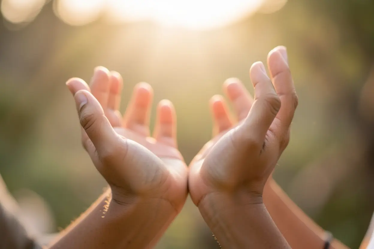 Mãos abertas recebendo luz, simbolizando graça