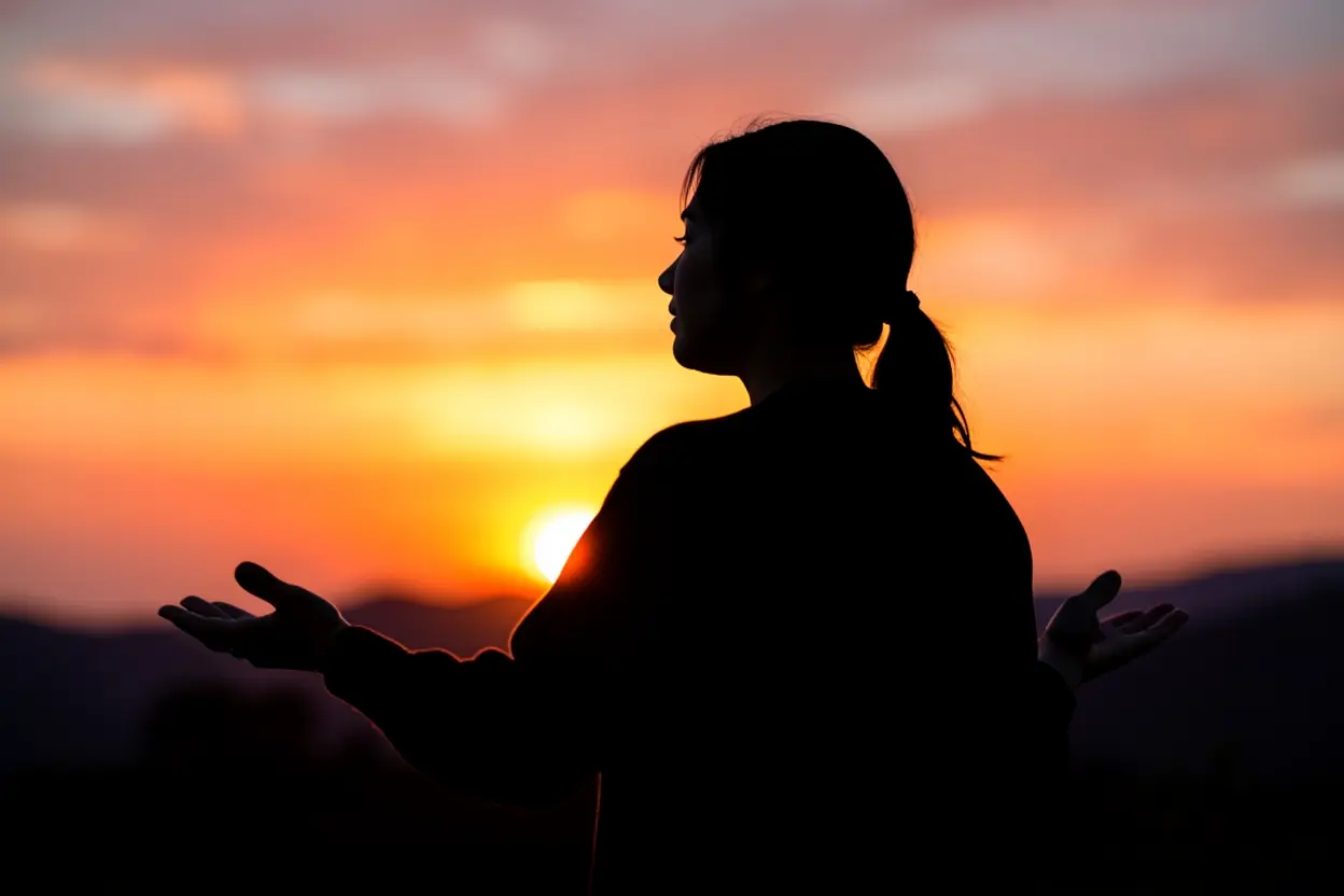 Silhueta de mulher adorando ao sol, simbolizando a intimidade com Deus.